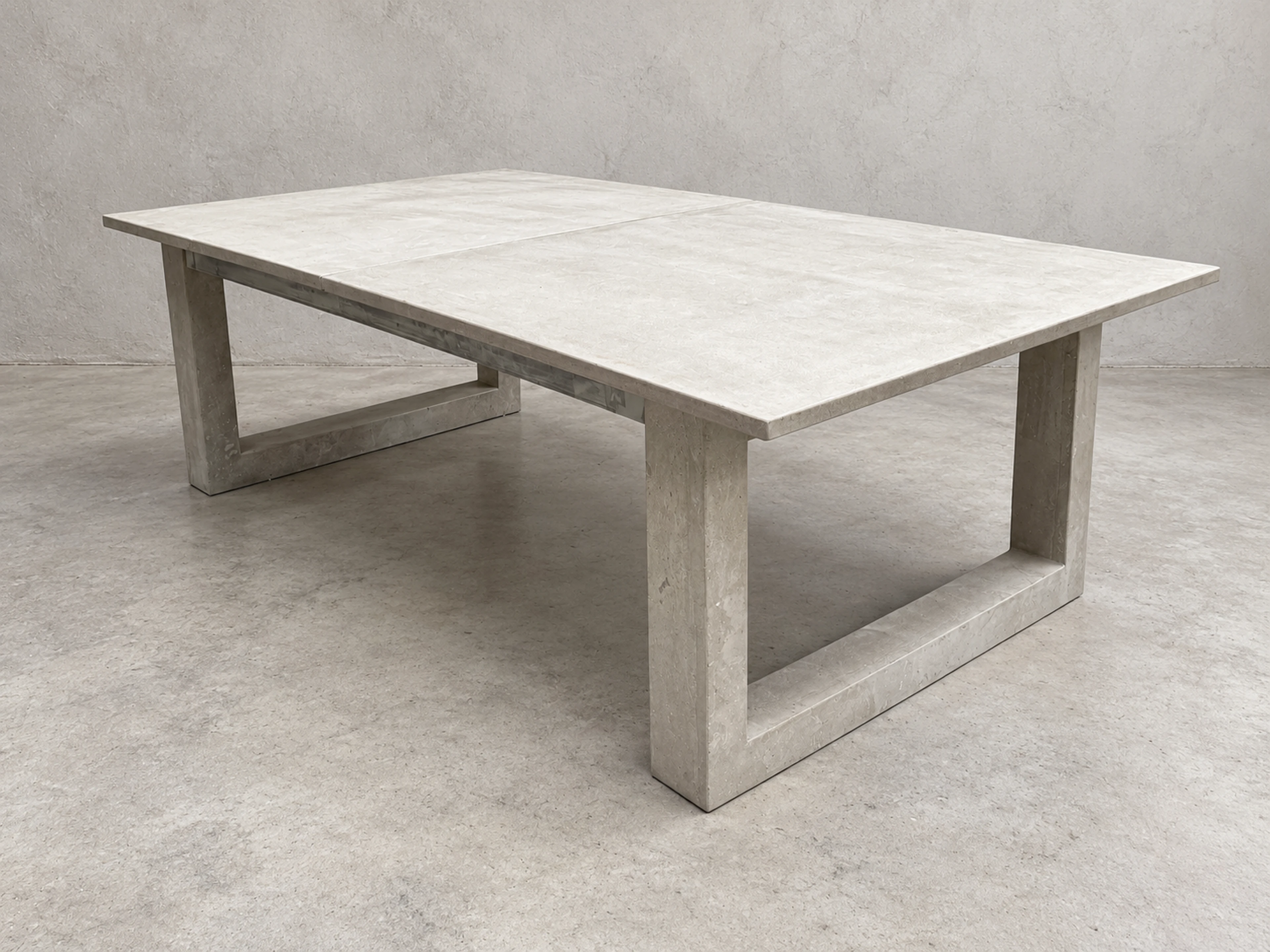 Mesa de centro rectangular baja de concreto gris claro con patas en forma de U, sobre fondo neutro