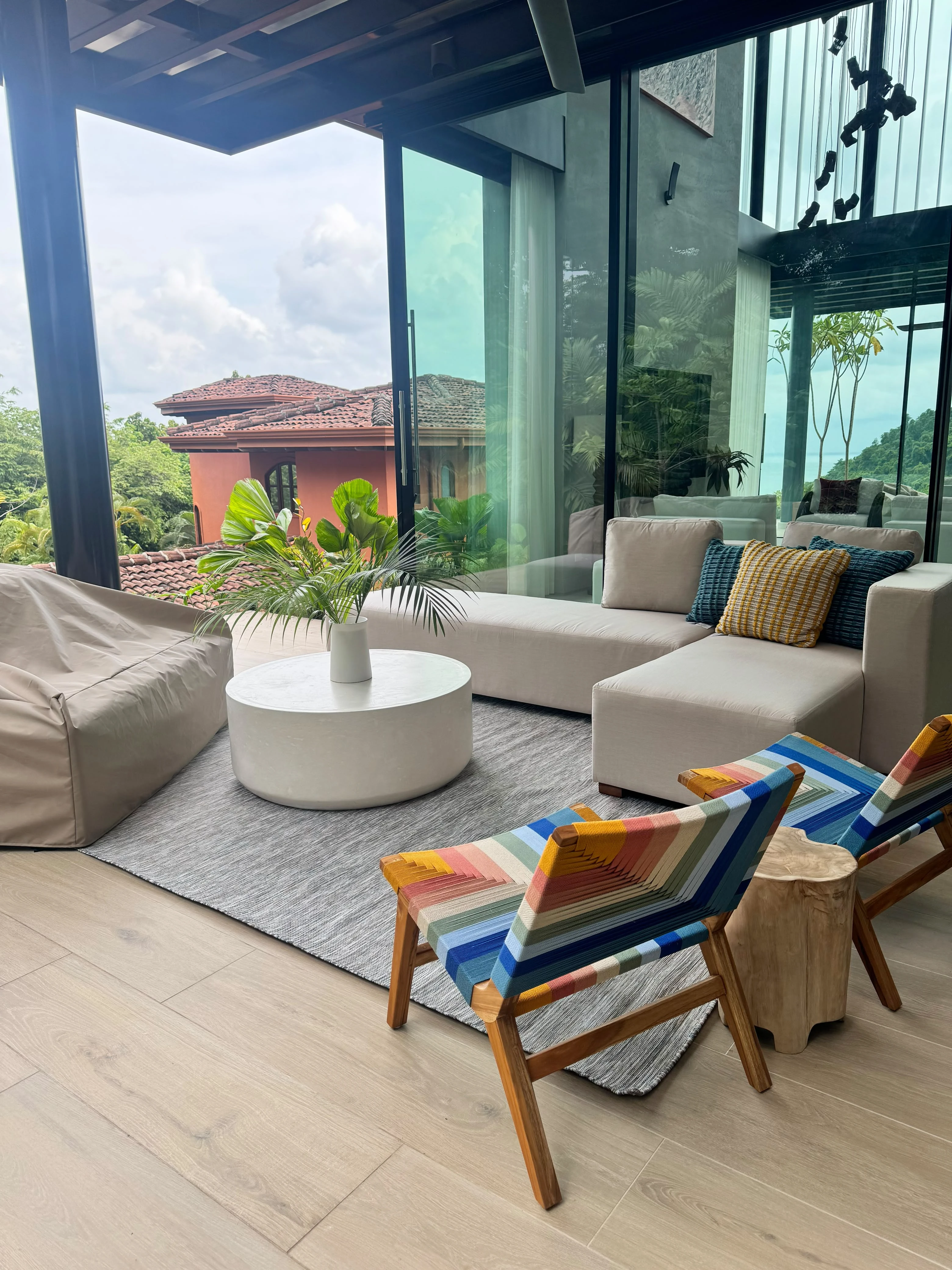 Mesa de centro redonda de concreto blanco en sala exterior con sofá, sillones coloridos y vista a las montañas