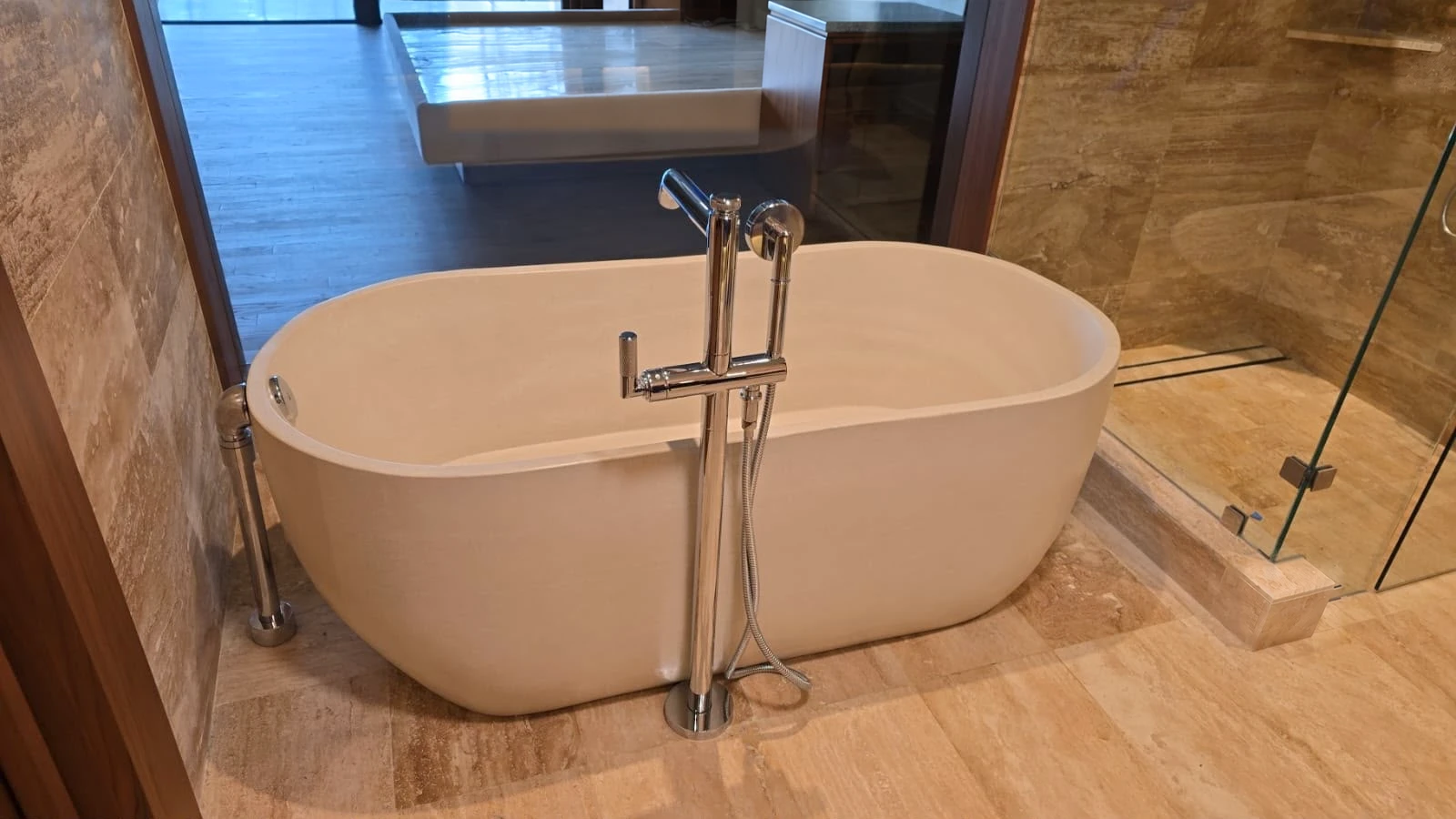 Tina Avellanas de concreto claro instalada en un baño revestido en piedra
